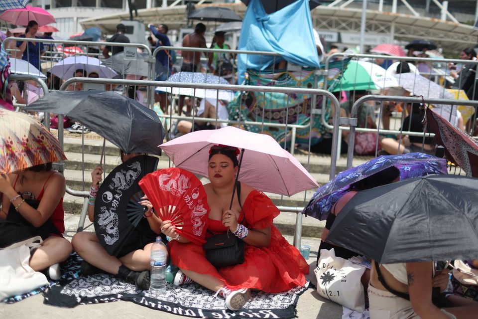 A girl using a fan waits among other people before the Taylor Swift concert, following the death of a fan due to the heat during the first day concert, in Rio de Janeiro, Brazil, November 18, 2023. REUTERS/Pilar Olivares