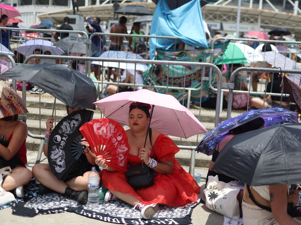 A girl using a fan waits among other people before the Taylor Swift concert, following the death of a fan due to the heat during the first day concert, in Rio de Janeiro, Brazil, November 18, 2023. REUTERS/Pilar Olivares
